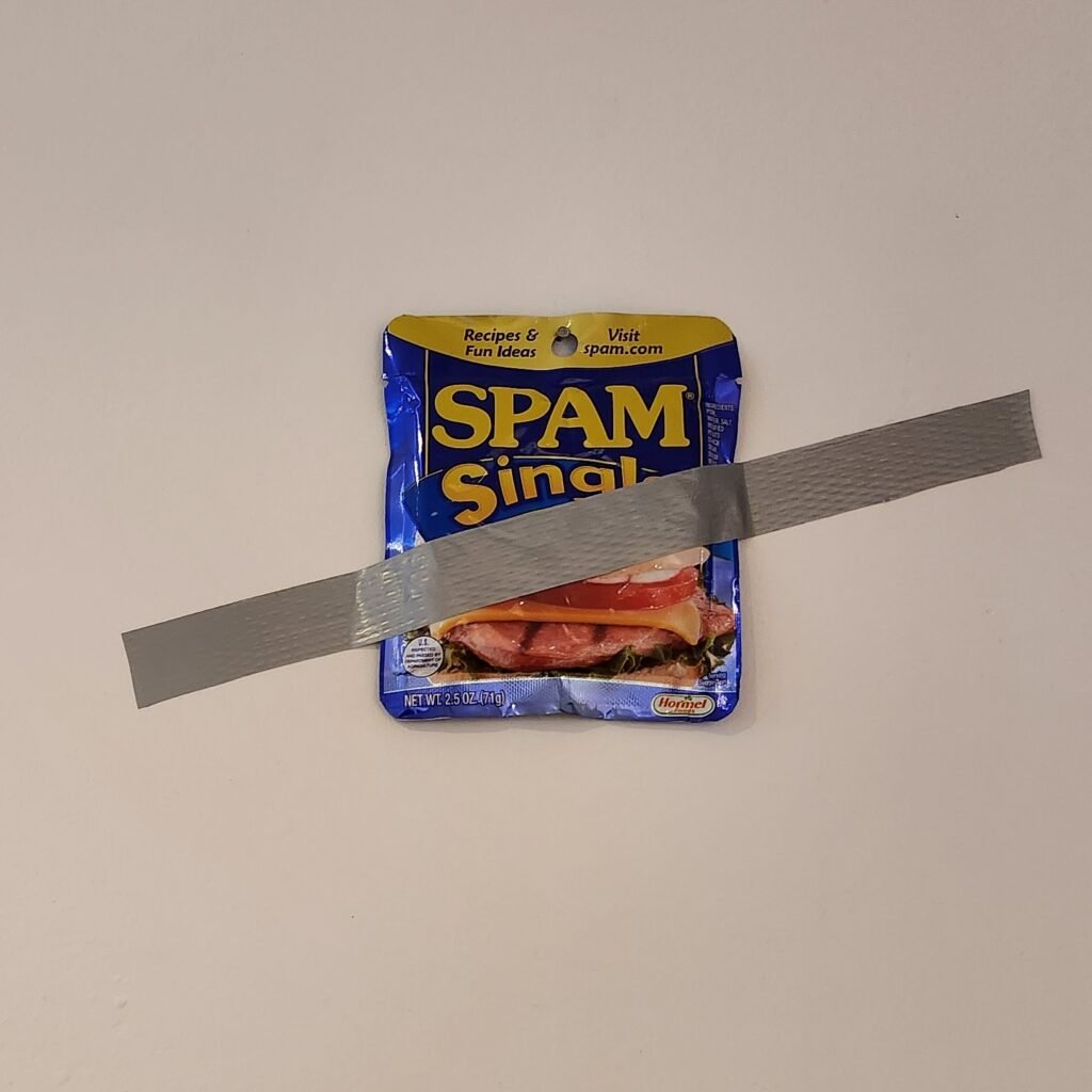 Spam singles pack taped to the wall with duct tape
